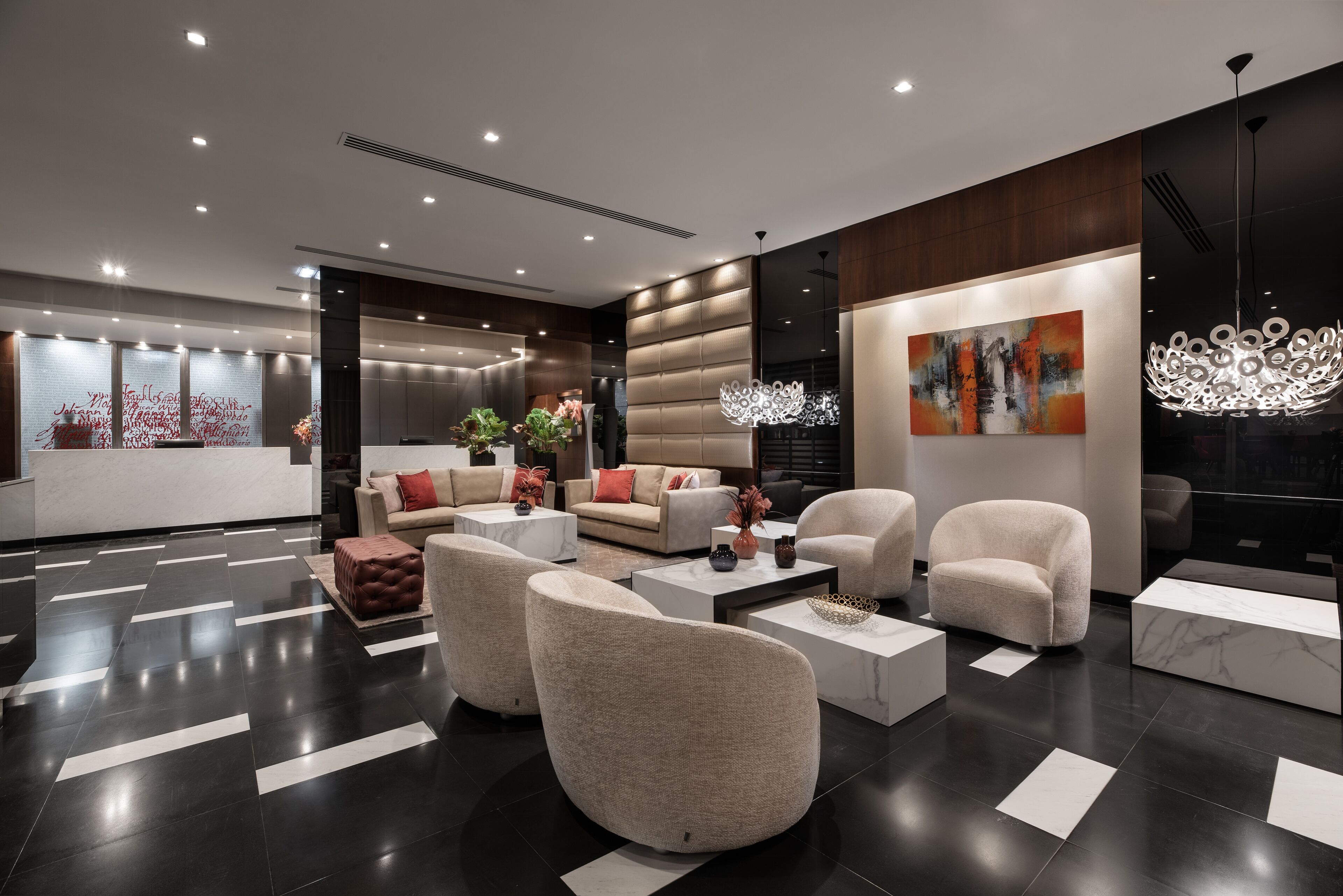 A modern lobby with a dark tiled floor, a large abstract painting, and a unique chandelier.
