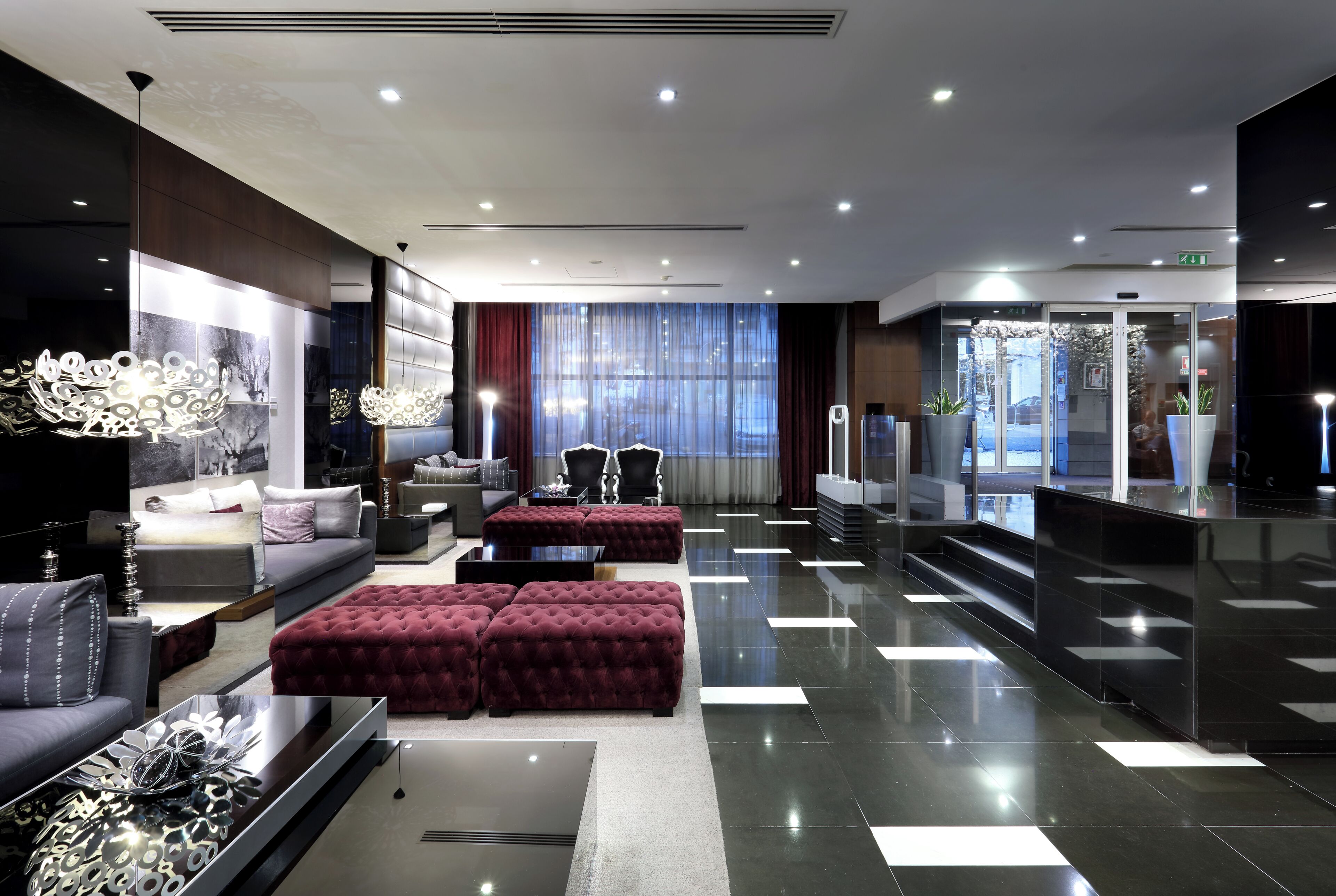 Un vestíbulo de hotel moderno con zona de estar, mostrador de recepción y una escalera que conduce a los pisos superiores.