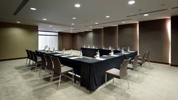 A conference room with a long table, chairs, and a carpeted floor.