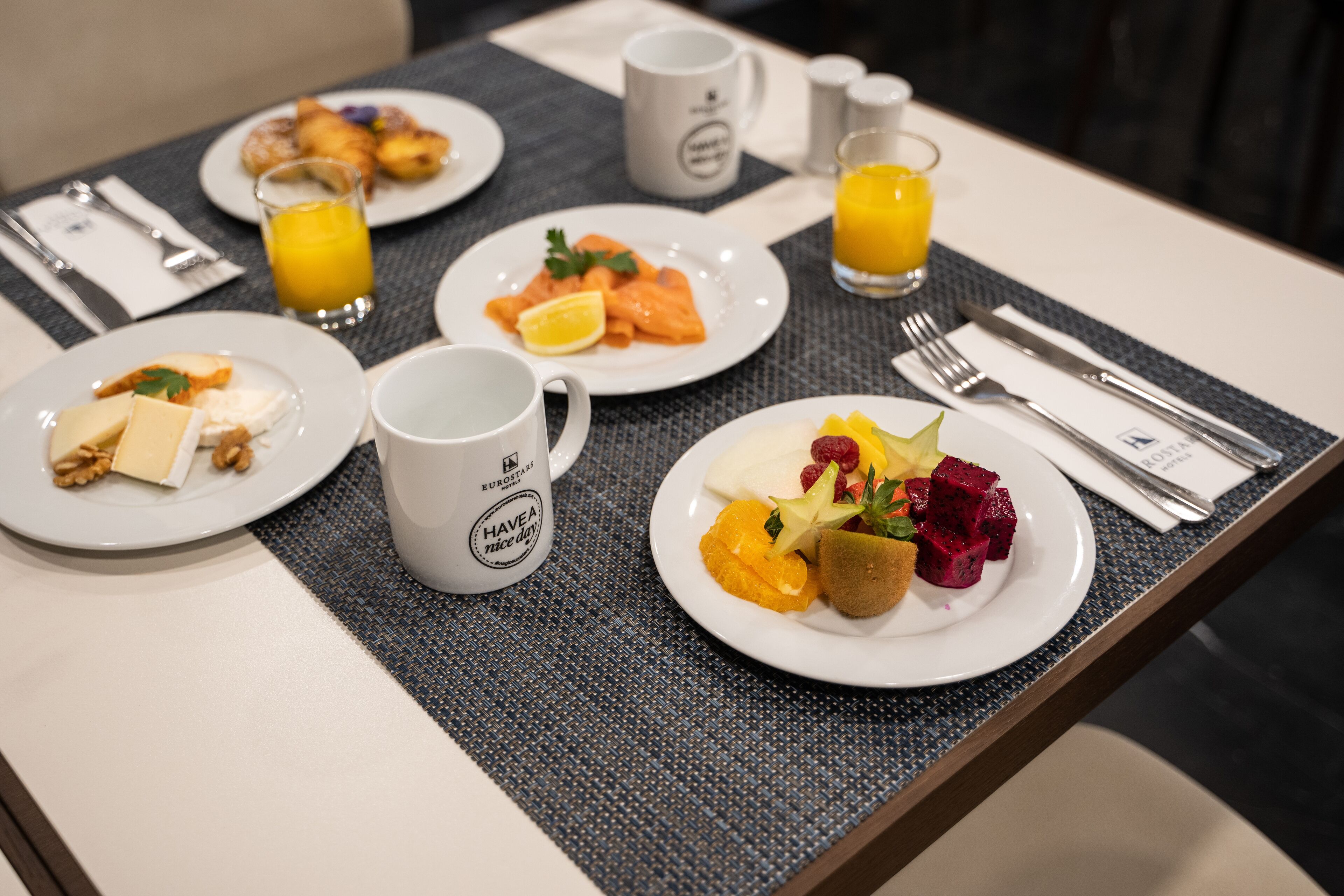 A breakfast setting with plates of food, a coffee mug, and a glass of orange juice on a table.