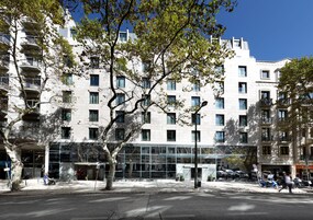 Un edificio moderno con varios pisos, ventanas amplias y balcones.