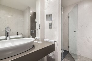 Un bagno moderno con un lavandino capiente, cabina doccia in vetro e pareti in marmo.