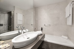 A modern bathroom with two sinks, a shower, and a bathtub.