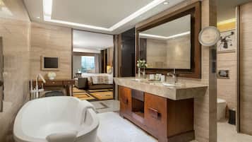 A modern bathroom with a freestanding bathtub, a large mirror, and a vanity with a marble countertop.
