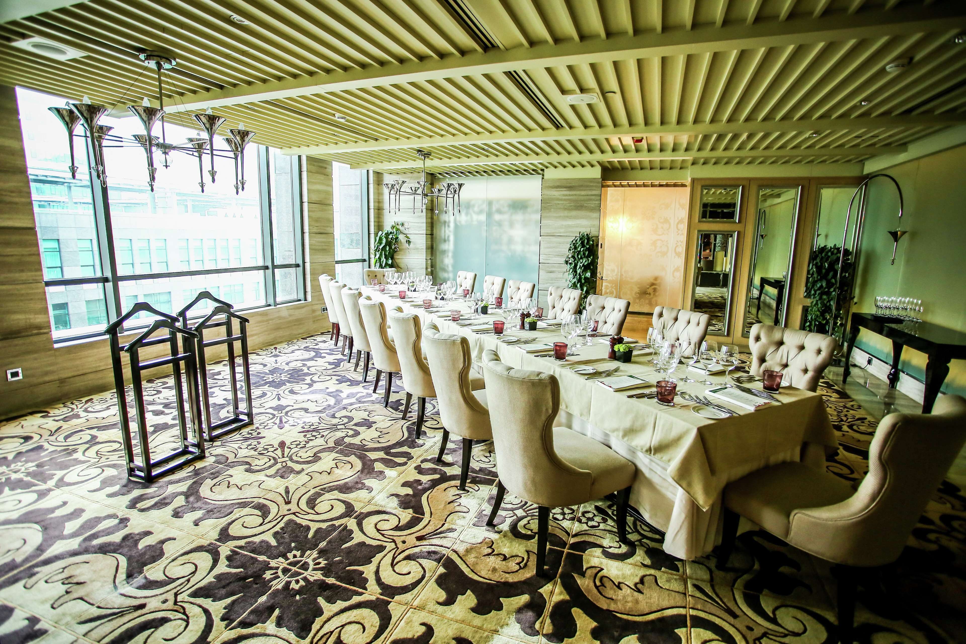 A dining area with a long table set for a meal, surrounded by upholstered chairs.