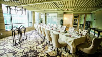 A dining area with a long table set for a meal, surrounded by upholstered chairs.