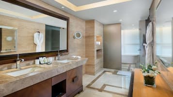 A modern bathroom with a large mirror, two sinks, a vanity, and a shower area.