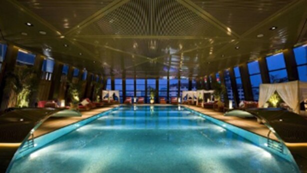 Una amplia piscina interior con techos altos y ventanas grandes.