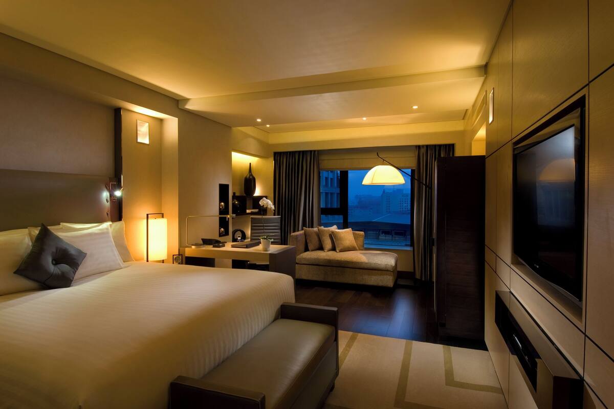 A hotel room with a large bed, a sofa, a desk, and a TV.