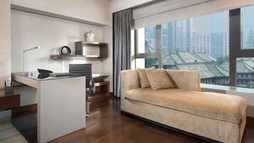 A modern living room with a sofa, a desk, and a large window with a city view.