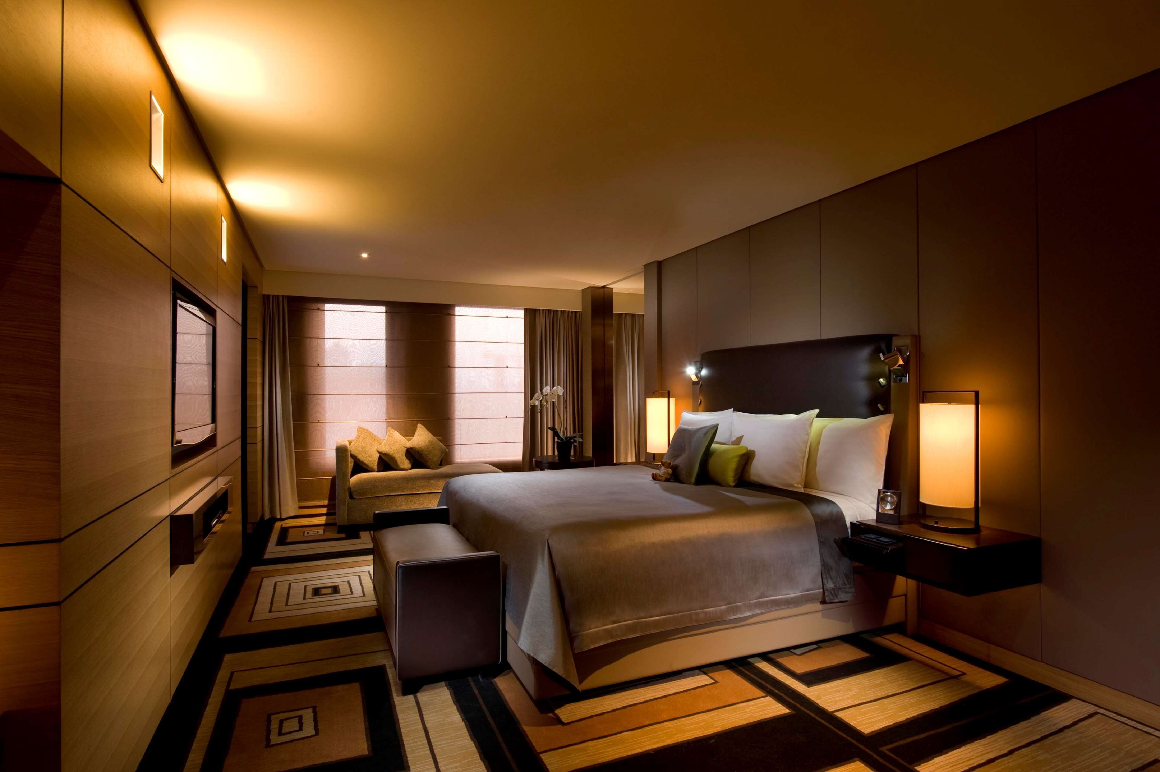 Quarto de hotel com uma cama grande, mesas de cabeceira e uma janela com cortinas.