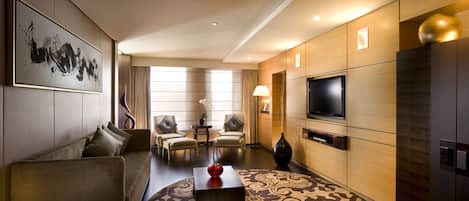 A modern hotel room with a sofa, chairs, a TV, and a decorative vase.
