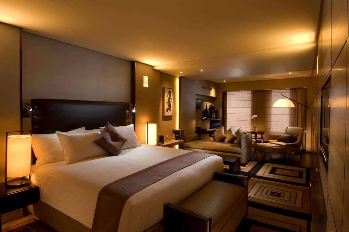 A hotel room with a large bed, a seating area with chairs, a small table, and a lamp.