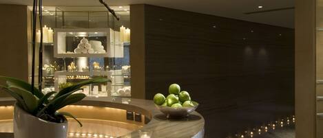 A modern reception area with a marble counter, a potted orchid, and a bowl of green apples.