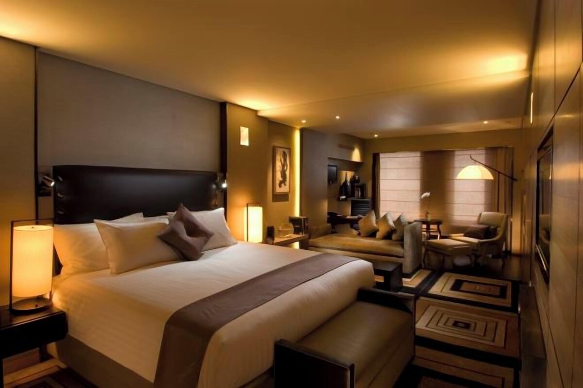 A hotel room with a large bed, a desk, and a seating area with chairs.