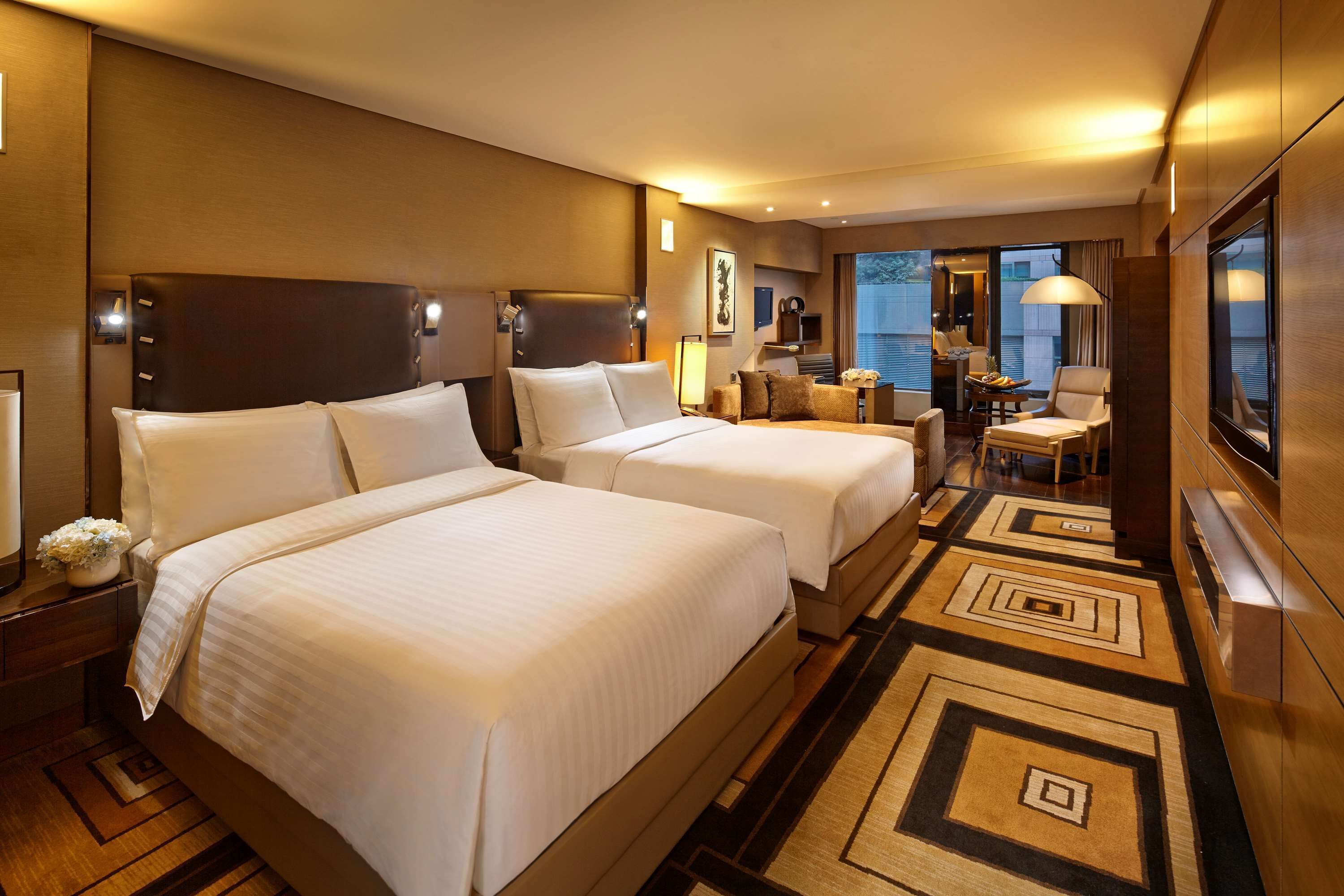 Une chambre d’hôtel avec deux lits, un bureau et une vue sur la ville.