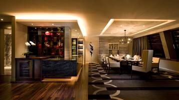 Un moderno vestíbulo de hotel con mostrador de recepción, una zona de bar con detalles rojos y un comedor con candelabro.