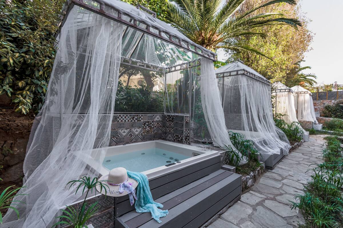 A hot tub with a canopy, surrounded by plants and a stone pathway.
