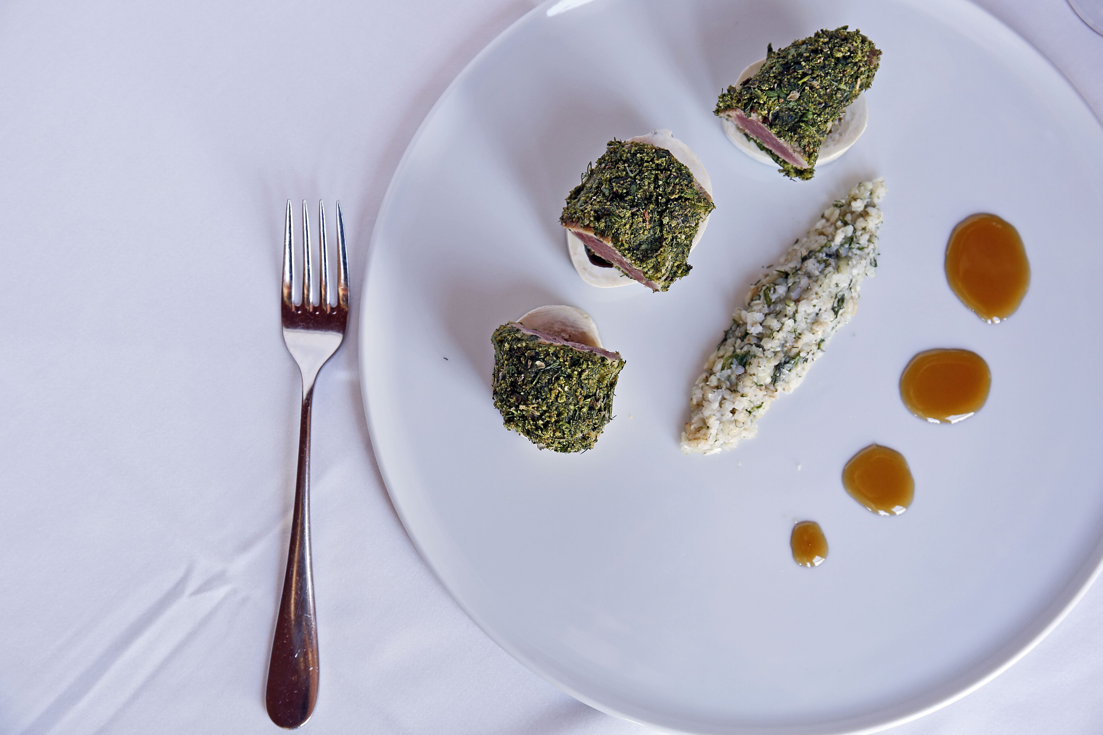 Une assiette blanche contenant des aliments et une fourchette, le tout posé sur une nappe blanche.