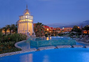 A resort pool area with a large, ornate gazebo, palm trees, and a mountain backdrop. - Orpheas Resort - Adults Only (Apokoronas)