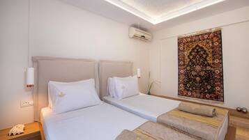 A hotel room with two beds, a large decorative tapestry, and an air conditioning unit.