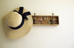 Un sombrero de paja con un lazo oscuro colgado en una pared.