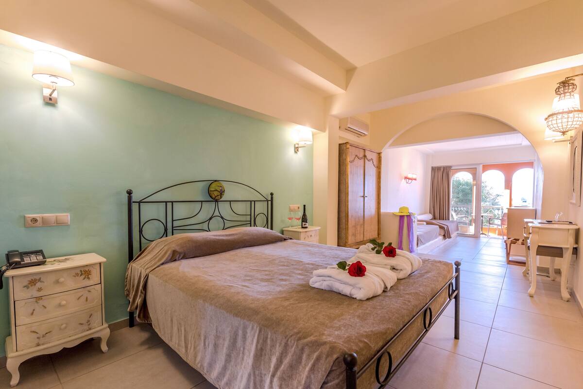 A bedroom with a bed, bedside tables, a lamp, and a view of the outside.