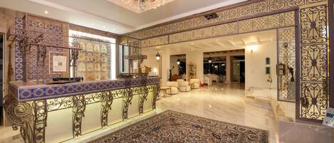 A spacious lobby with a decorative bar, patterned walls, and a chandelier.