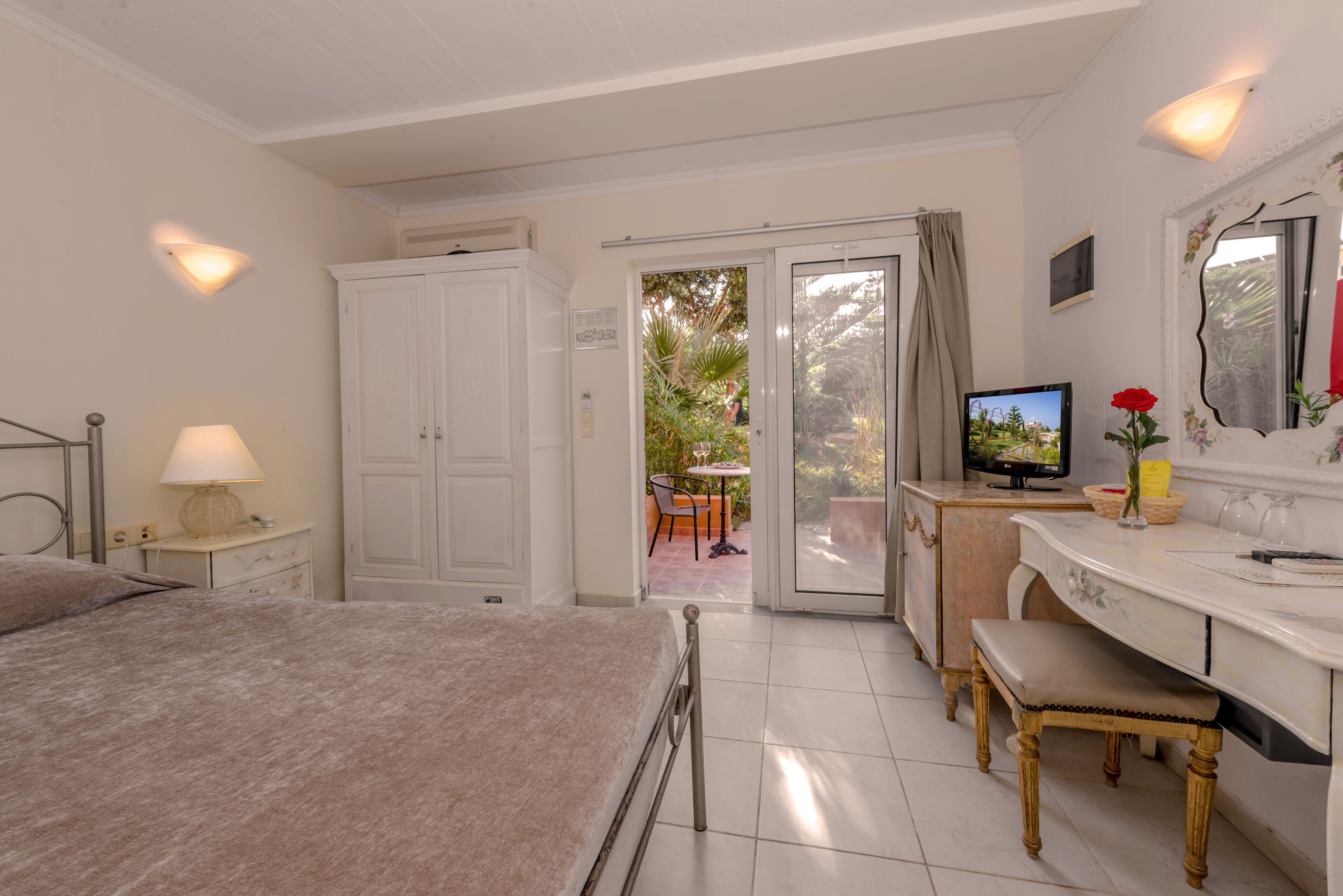 A bedroom with a bed, a desk, a television, and a bathroom with a shower.