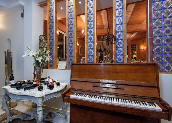 A piano with a decorative vase of flowers and a wine bottle on a table. - Orpheas Resort - Adults Only (Apokoronas)