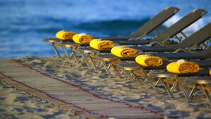 Beach chairs with yellow towels folded on them, arranged in rows on a wooden deck with red safety markers. - Orpheas Resort - Adults Only (Apokoronas)