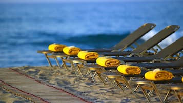 En privat strand, liggestole, parasoller, badehåndklæder