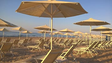 Een privéstrand, ligstoelen aan het strand, parasols, strandlakens