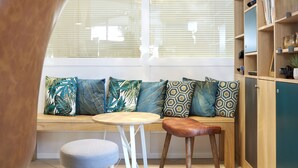 A cozy seating area with a wooden bench, a round table, and two stools. - Aparthotel Adagio Access Carrières-sous-Poissy (Carrieres-sous-Poissy)