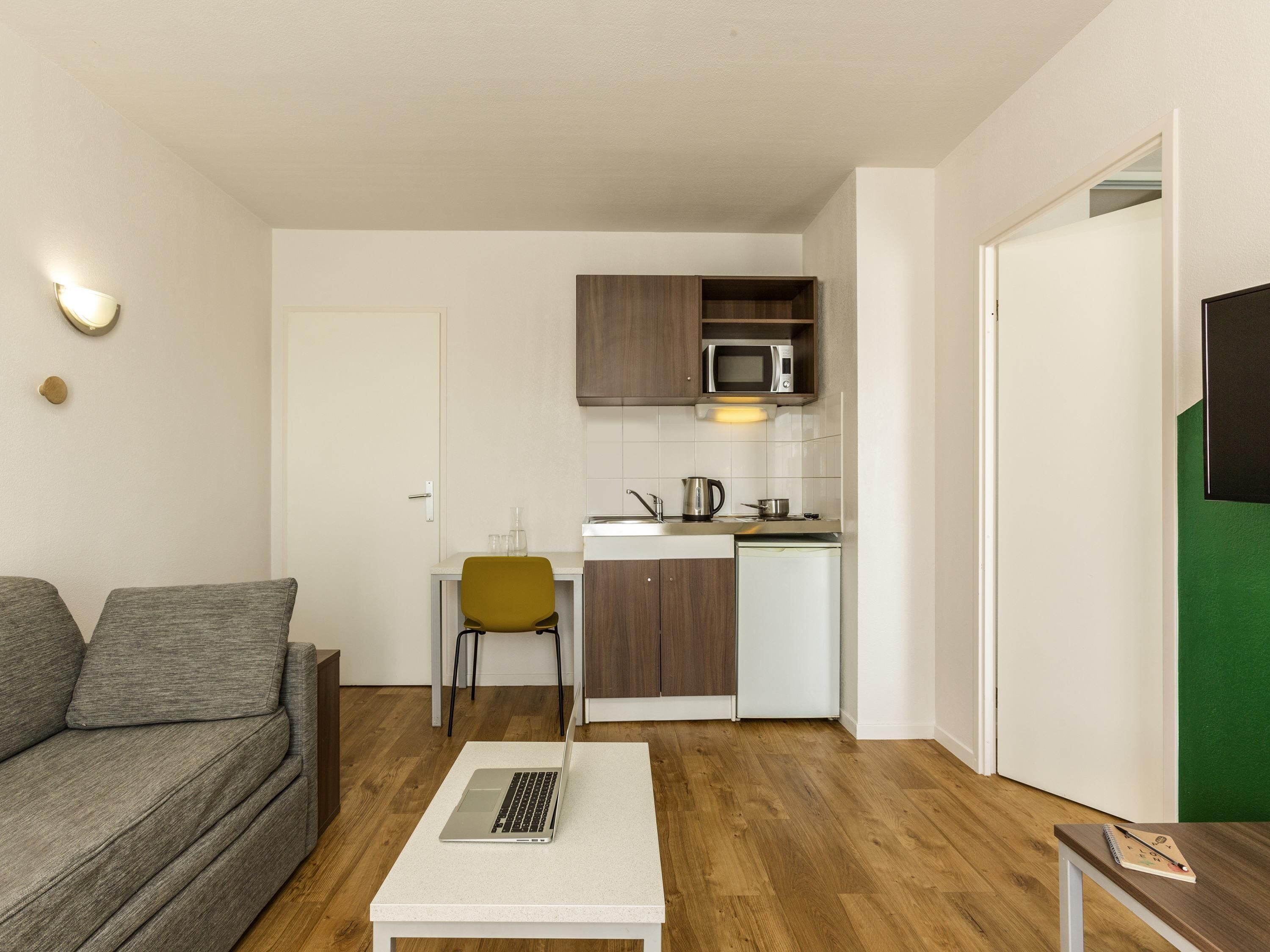 Un espace de vie compact comprenant un coin cuisine, un canapé, une table basse et une chaise.