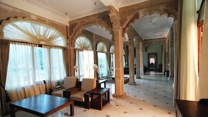 A spacious lobby with a high ceiling, ornate arches, and a seating area with a sofa and armchairs. - Fateh Bagh (Desuri)