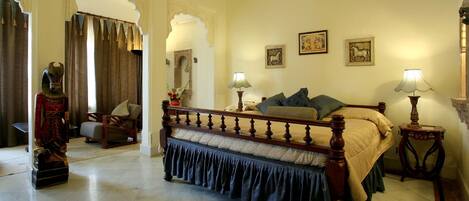 A traditional bedroom with a wooden bed, two bedside tables with lamps, a mirror, and artwork on the walls.