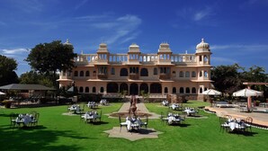 A large building with multiple dining areas, each with tables and chairs, set against a clear blue sky. - Fateh Bagh (Desuri)