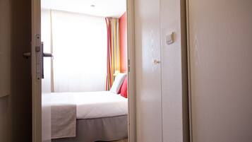 Una habitación de hotel con cama, una puerta y un ventanal con cortinas.