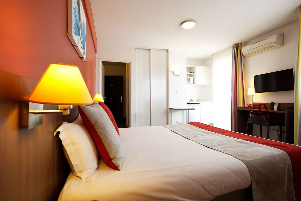 Habitació d'hotel amb un llit, escriptori, cadira, televisió i microones.