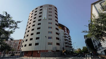 A multi-story hotel with a curved facade, multiple balconies, and a clear sky.