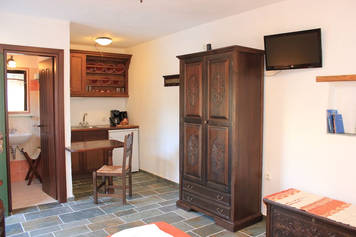 Cocina compacta con zona de comedor, un armario de madera y un televisor montado en la pared.