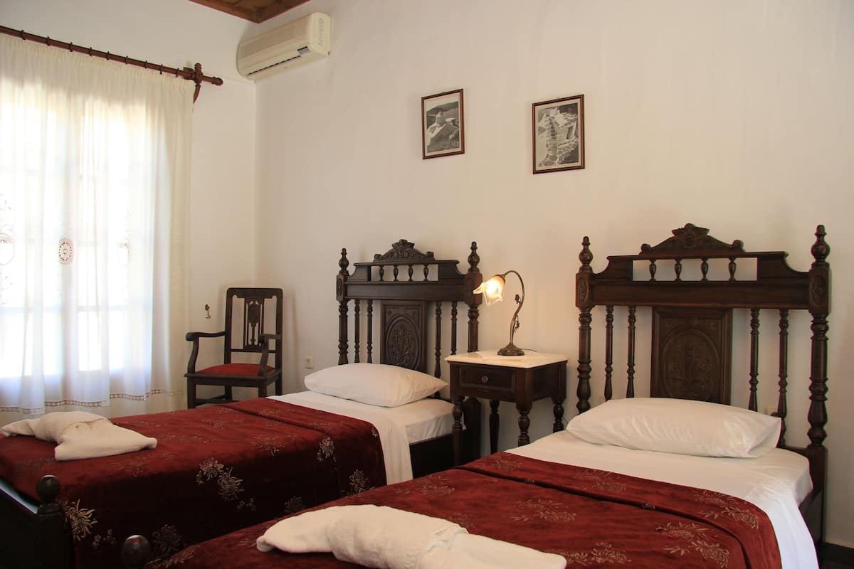 Una habitación con dos camas, una silla y una mesita de noche con lámpara.