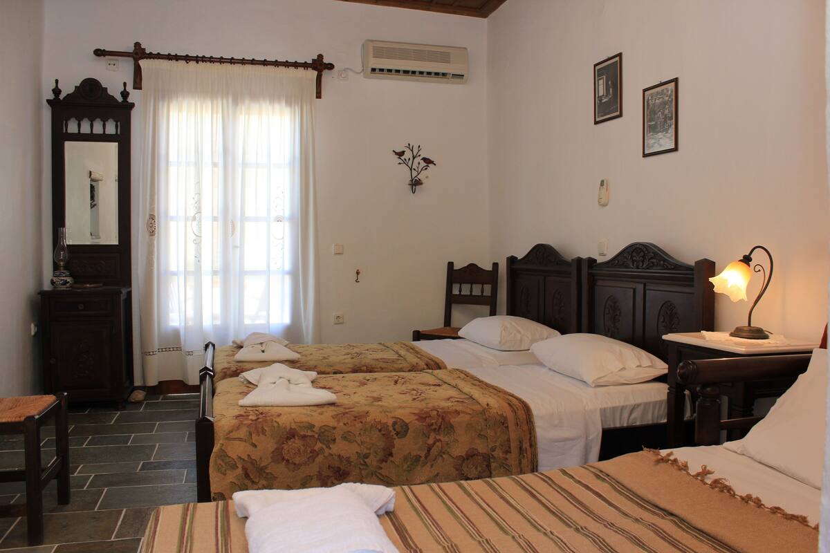 Un dormitorio con dos camas, un aparador, una silla y una mesita de noche con lámpara.