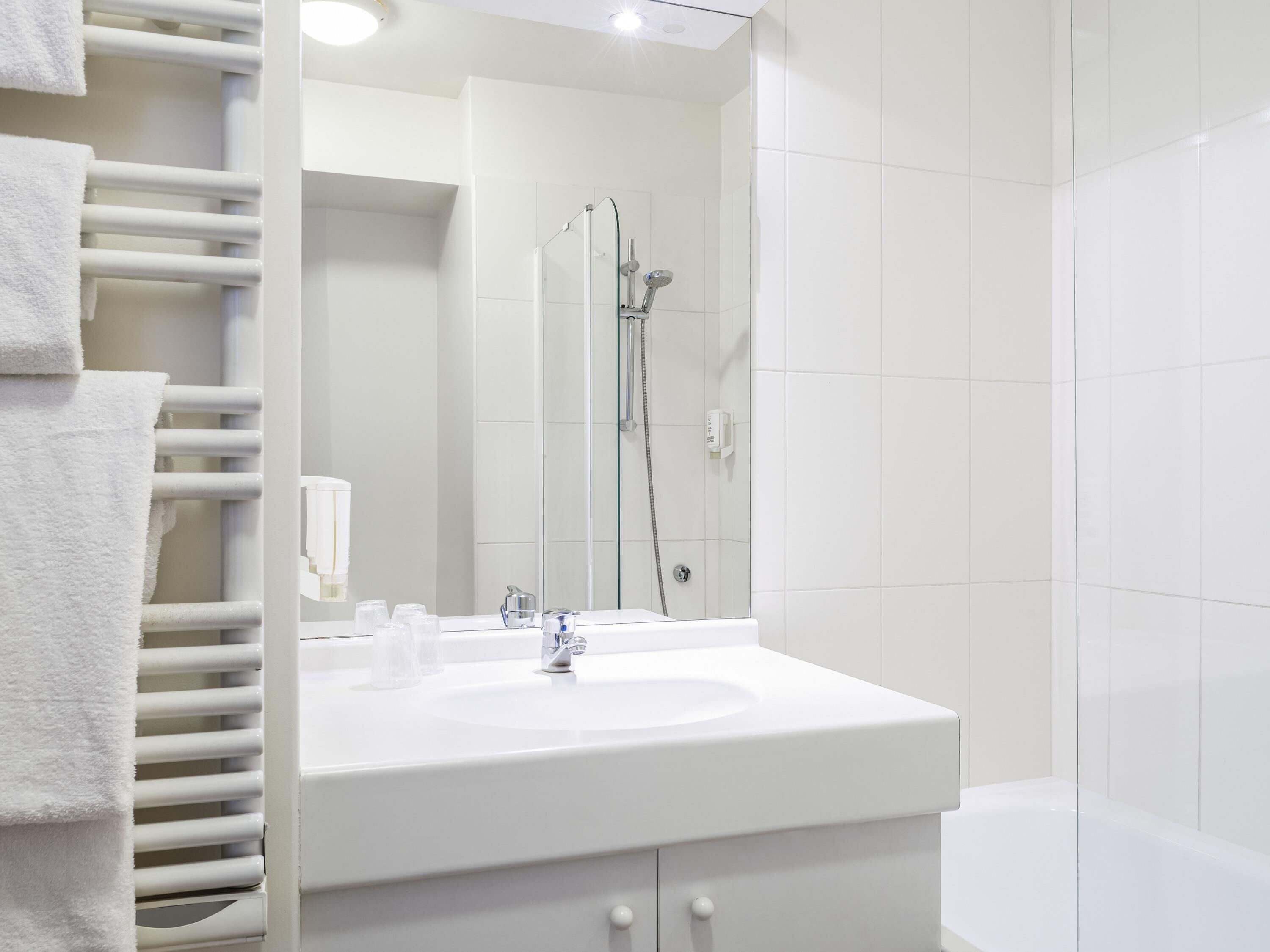 A modern bathroom with a white sink, mirror, and shower.