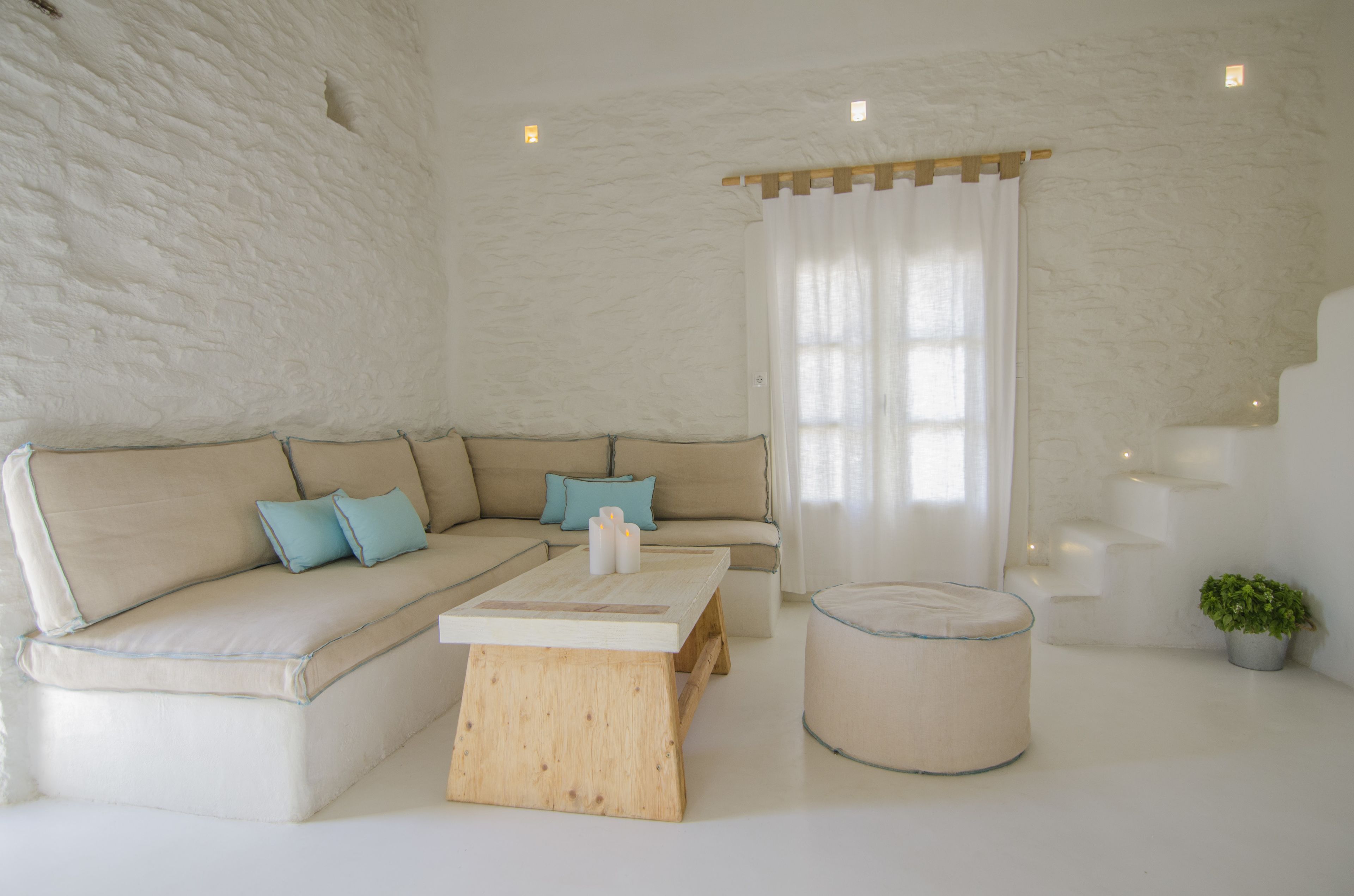 A modern living room with a beige sectional sofa, a wooden coffee table, and a round ottoman.