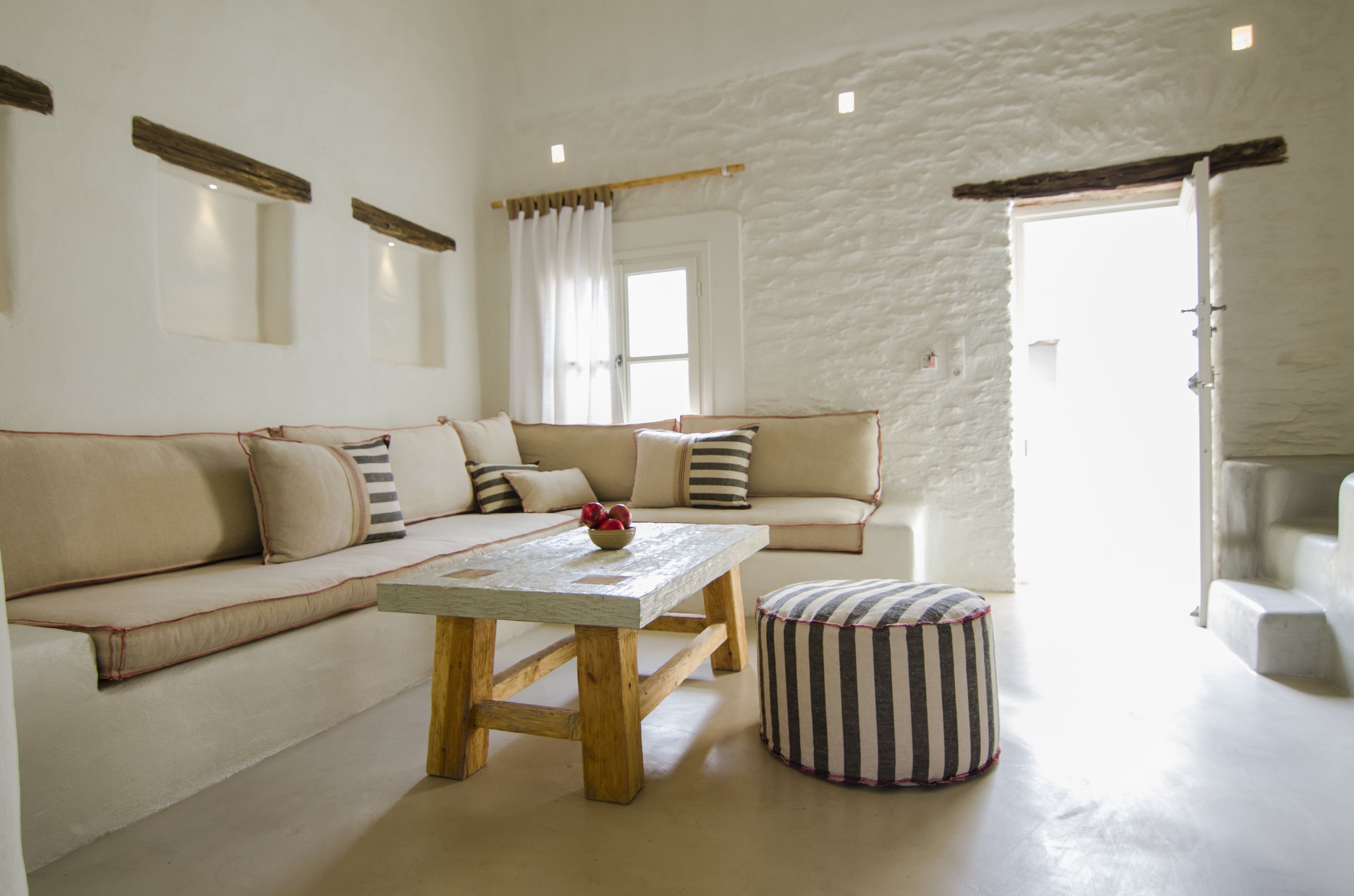 Ein Wohnzimmer mit einem beigen Sofa, einem Holztisch und einem gestreiften Ottoman.