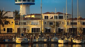 Un puerto deportivo con varias embarcaciones amarradas, un faro y un hotel con techo de tejas rojas.
