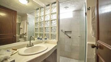 Un baño con un espejo grande, un lavabo y una cabina de ducha de vidrio.
