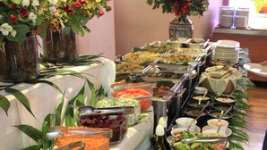 A buffet table with various food items and a vase of flowers.